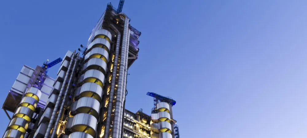 Modern high-rise building with cylindrical structures and exposed mechanical systems against a clear blue sky.