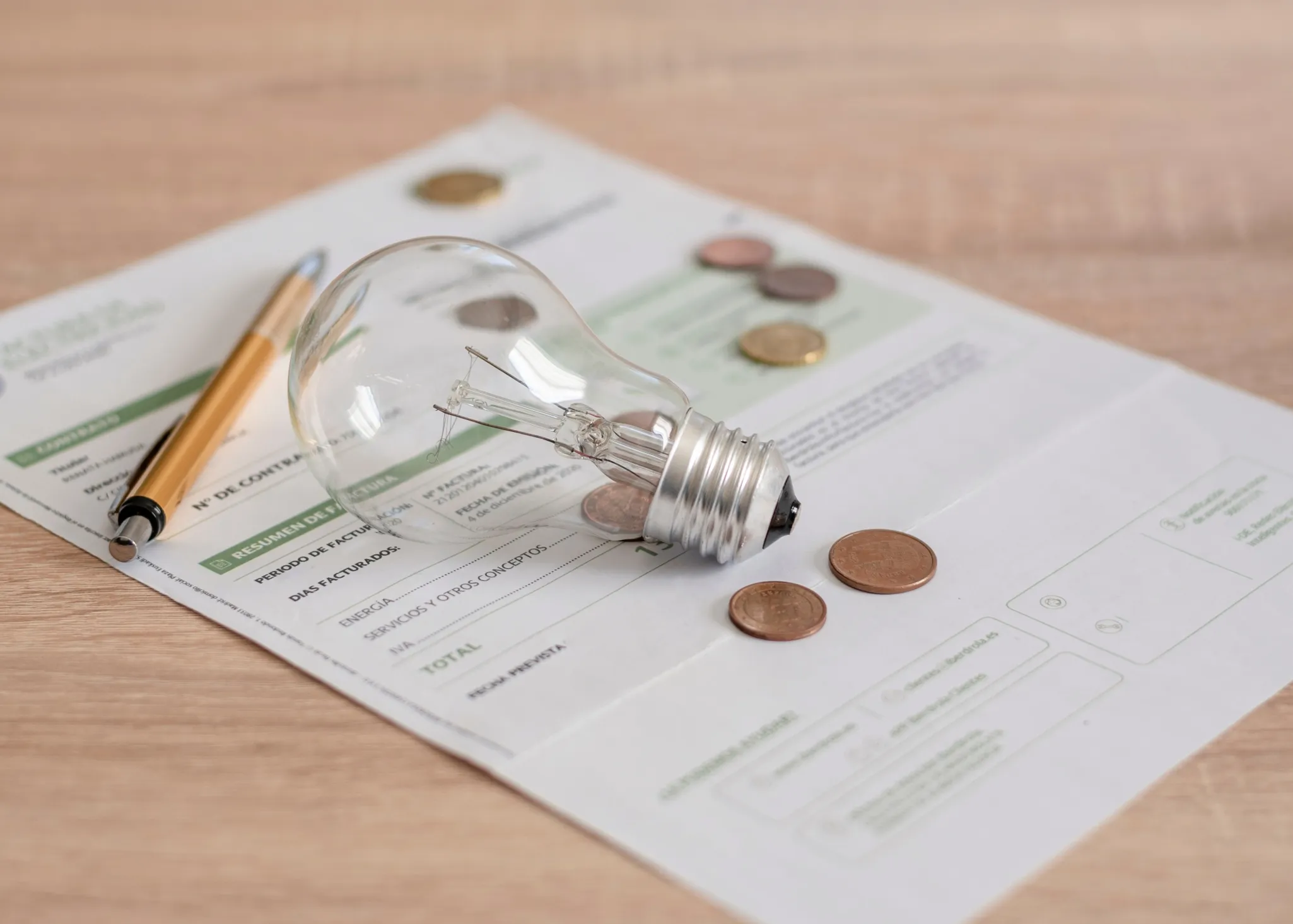 Light bulb, coins, and a pen placed on a utility bill document.