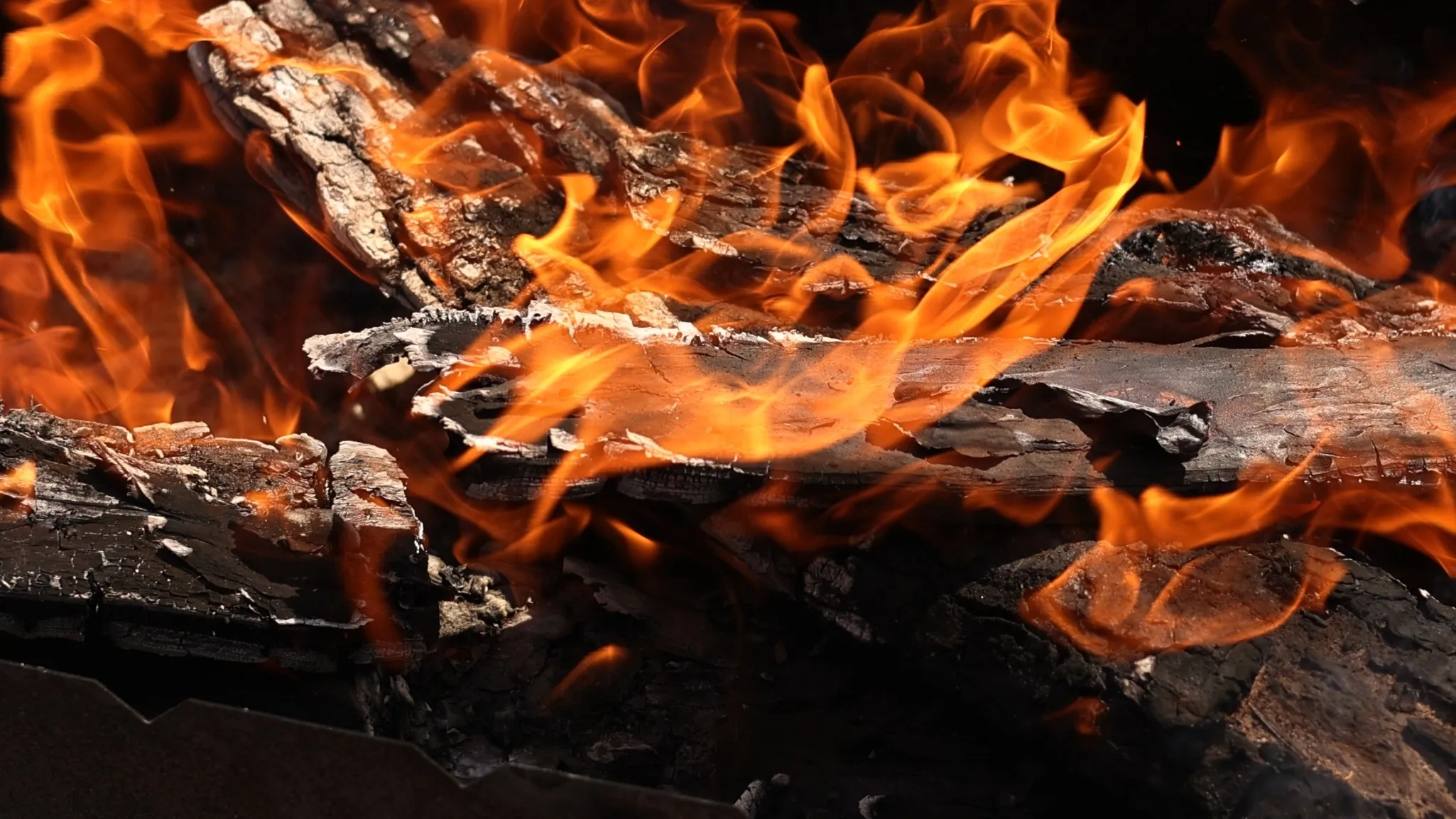 Close-up of burning wood logs with bright orange flames.