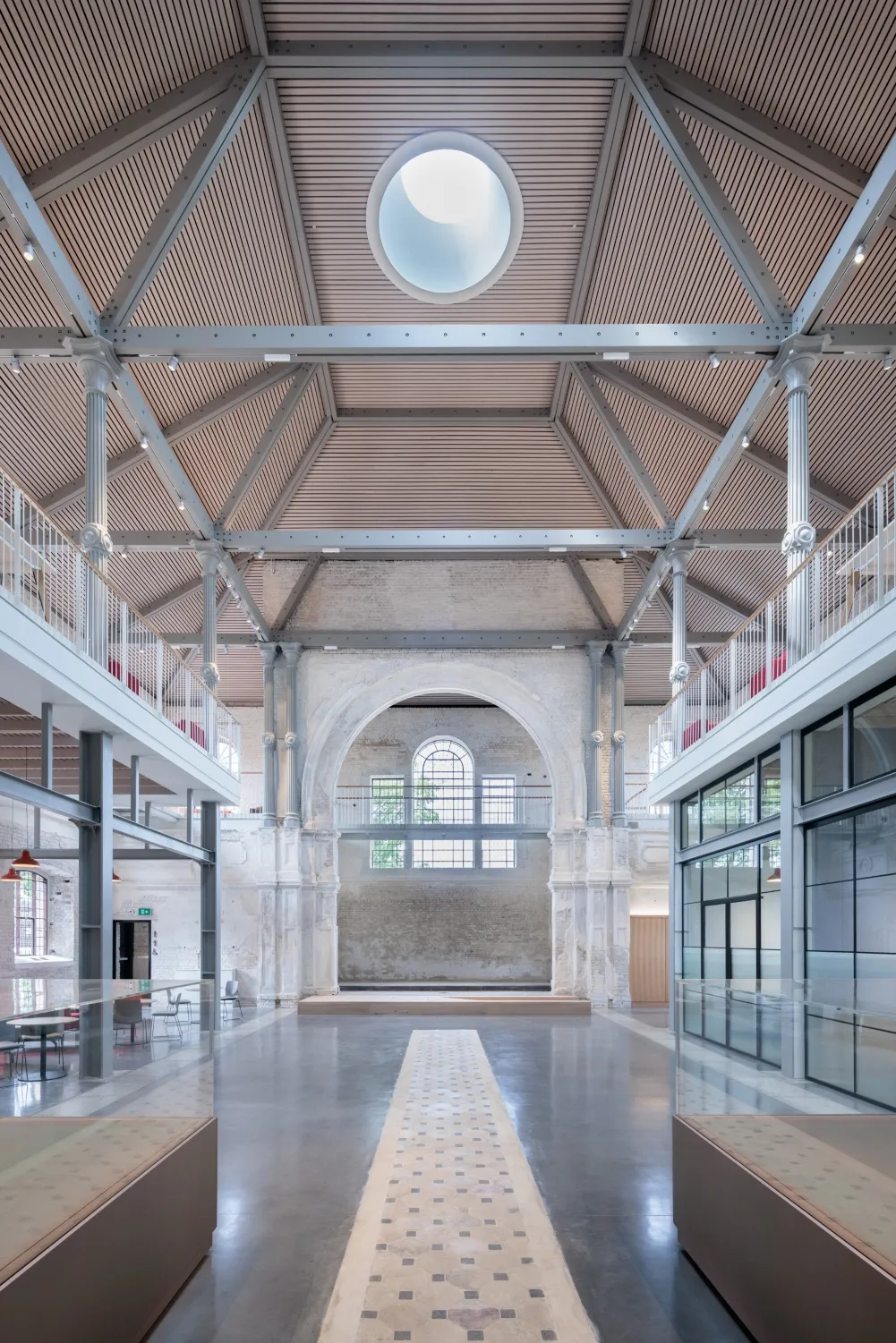 A spacious, modernized interior with high ceilings, exposed beams, a large central arch and a round skylight overhead.