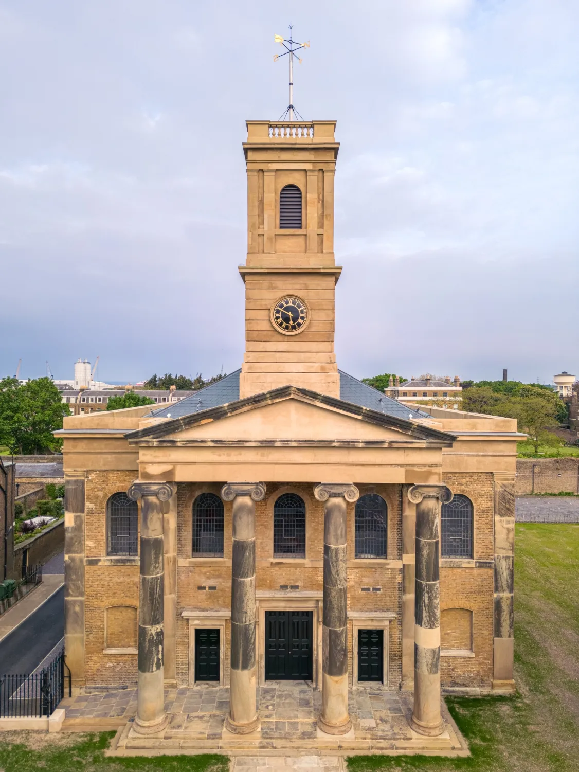 A neoclassical-style church with a prominent clock tower and large columns at the entrance. The sky is partly cloudy.