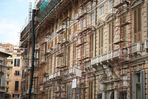 Scaffolding lines the exterior of a multi-story building under renovation in an urban area.