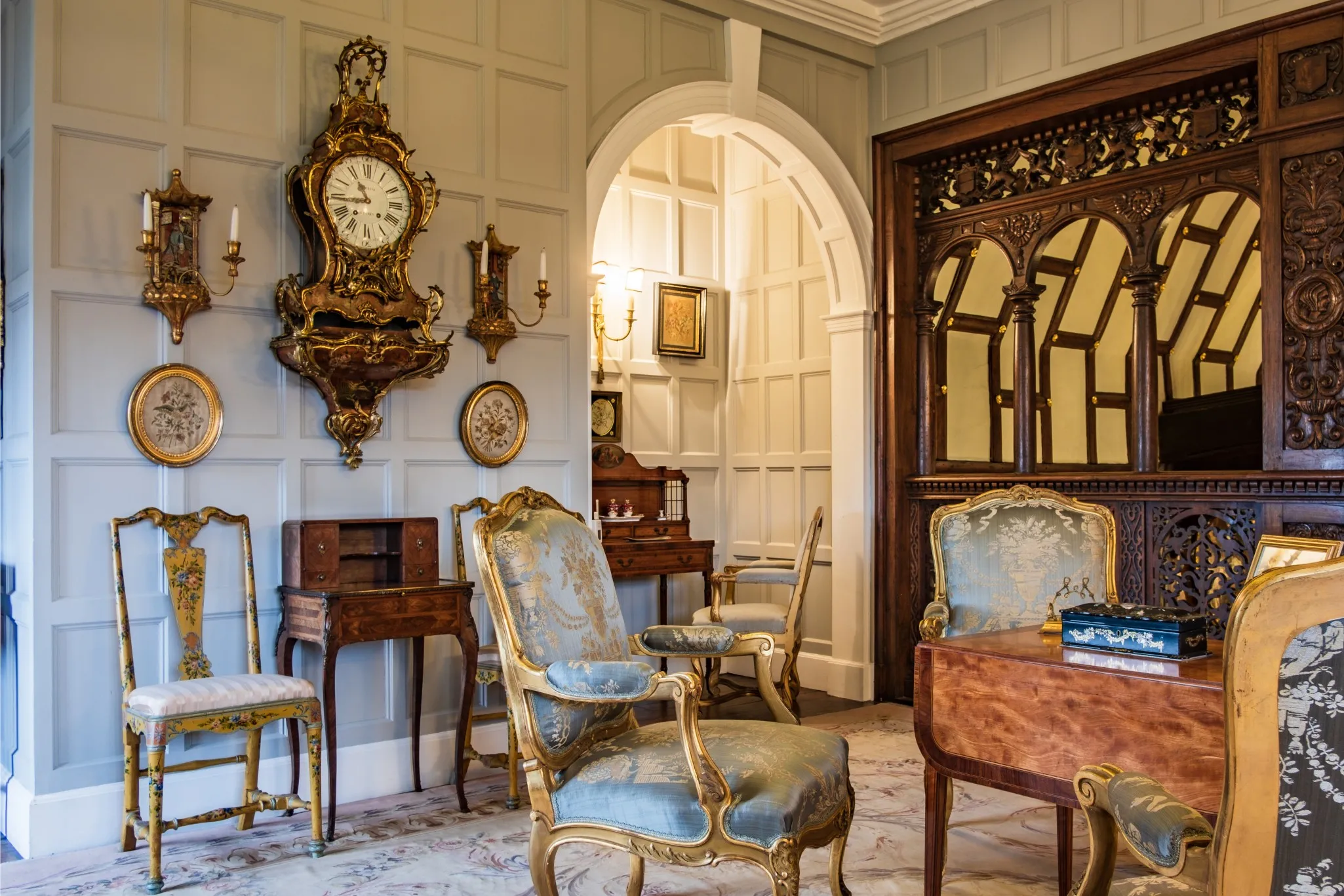 An ornate room with antique furniture and panelling. Features include an antique desk, chairs, and decorative items.