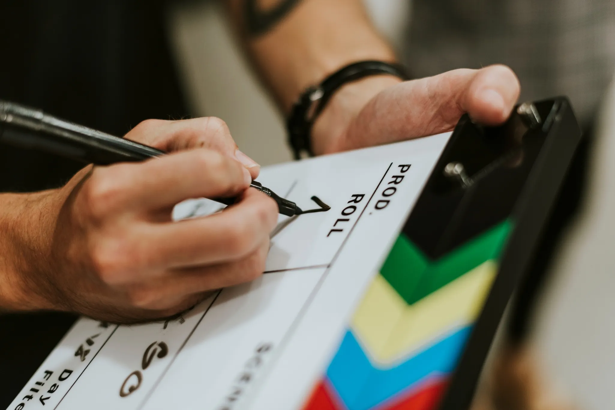 Close-up of a person writing on a clapperboard with a marker, indicating the start of filming.