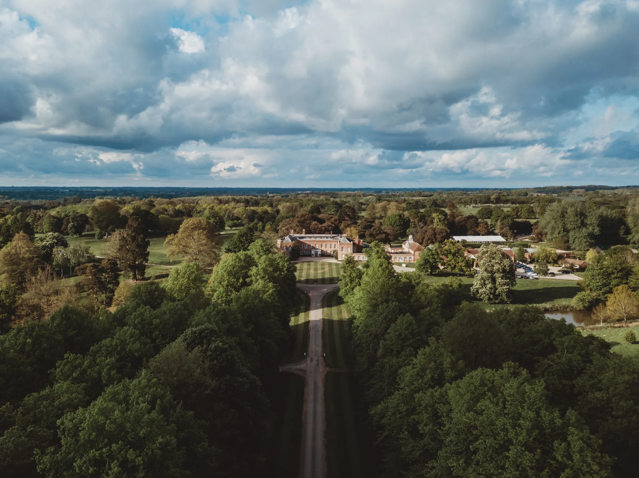 Aerial view of Braxted Park with surrounding greenery, and a long driveway extending through the trees.