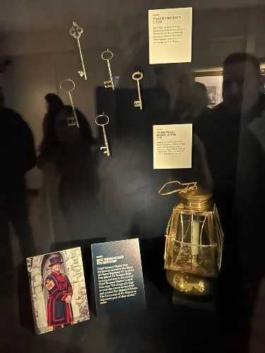 A display case contains several historical keys, explanatory plaques, a glass container, and a photograph of a ceremonial guard.