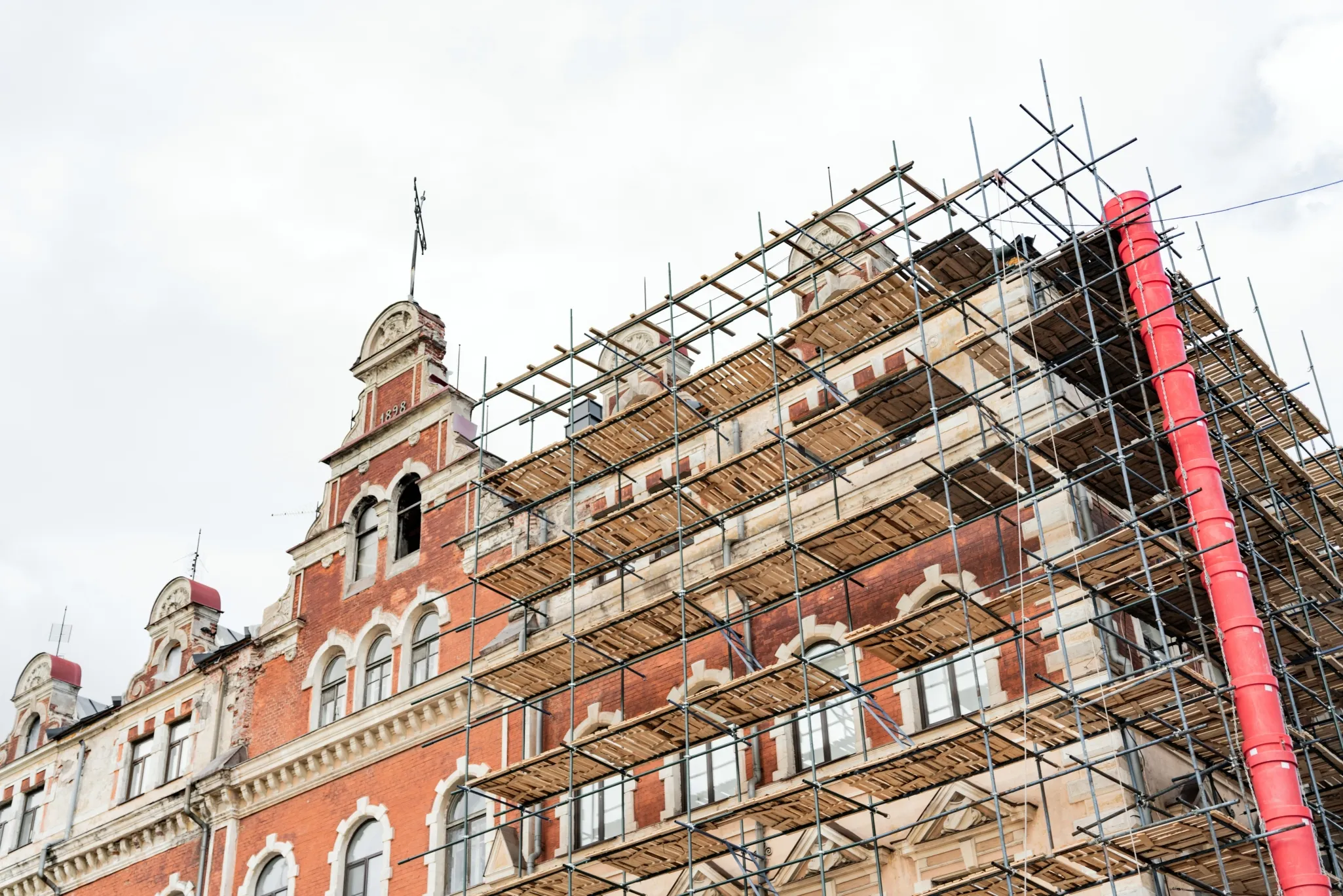 Historic building with ornate details undergoing renovation, featuring extensive scaffolding on its facade.