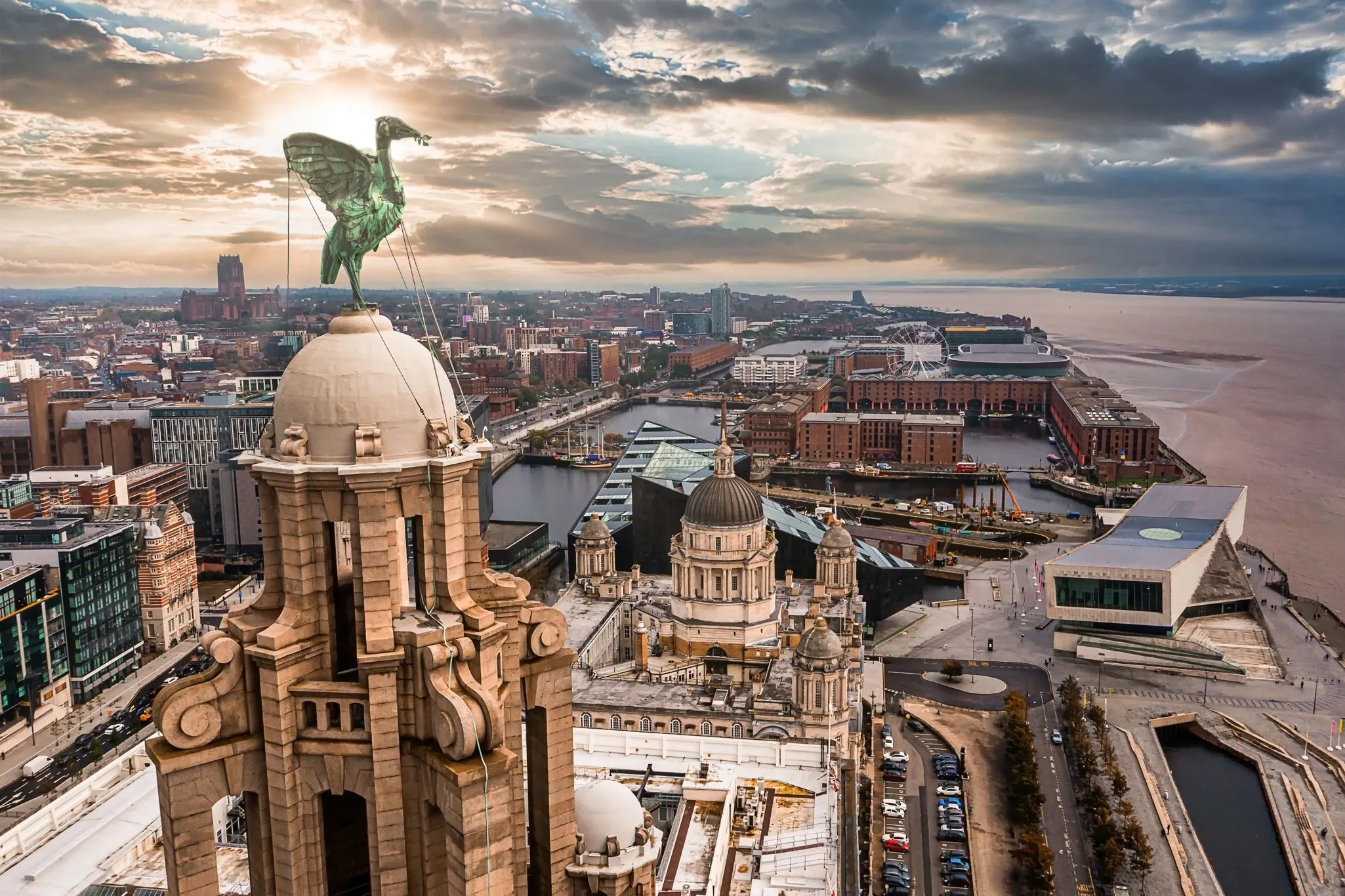 Aerial view of Liverpool, highlighting the Royal Liver Building with its Liver Bird statues against a backdrop of the city and waterfront.