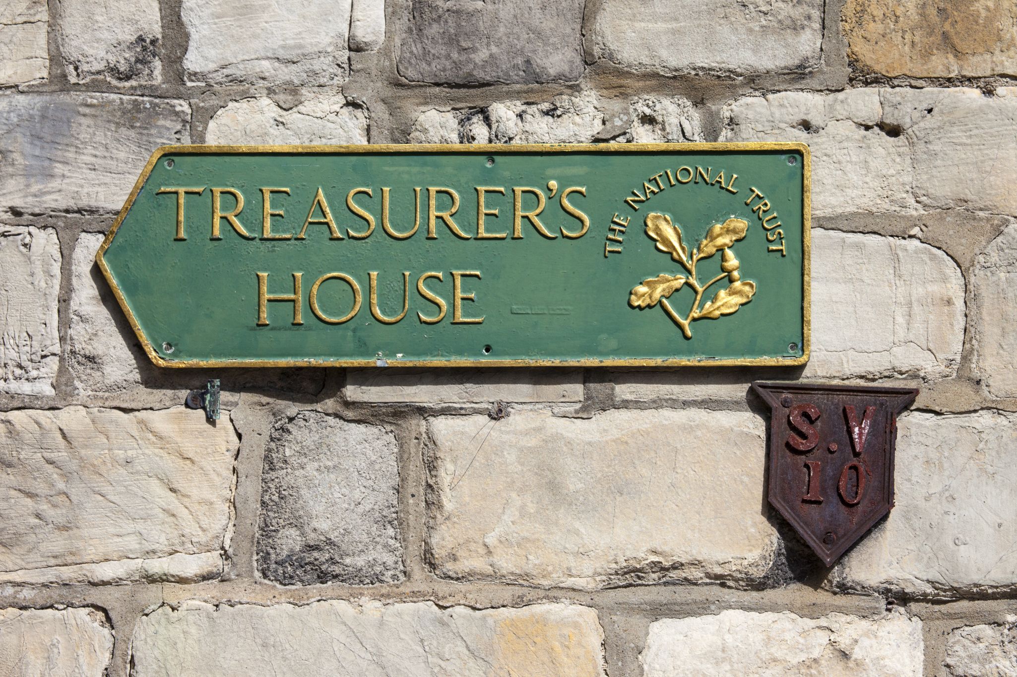 Green sign with gold lettering reading 